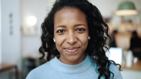 Laughing brunette African woman wearing blue sweater looking at the camera