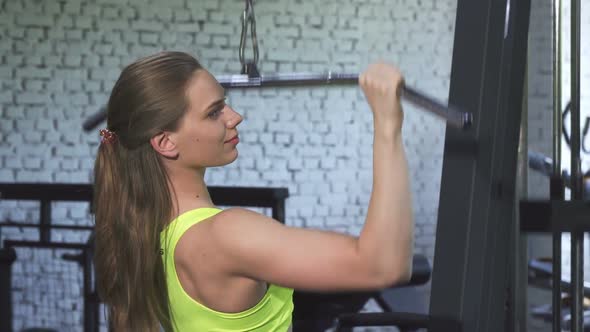 Attractive Athletic Woman Exercising on Lat Pulldown Cable Gym Machine