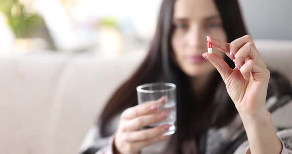 Sick Woman Holding Pill and Glass of Water Closeup