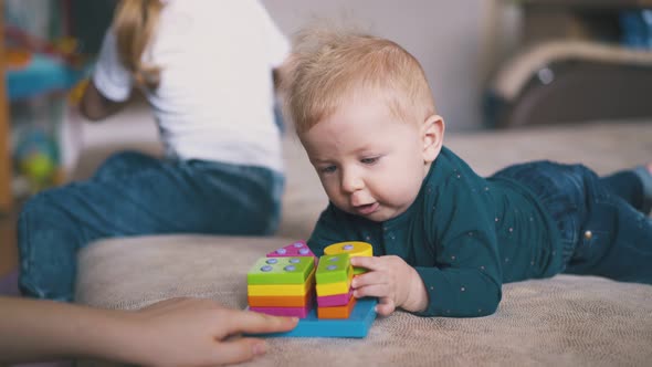 Boy Plays with Colorful Toy and Sister with Pyggybank on Bed