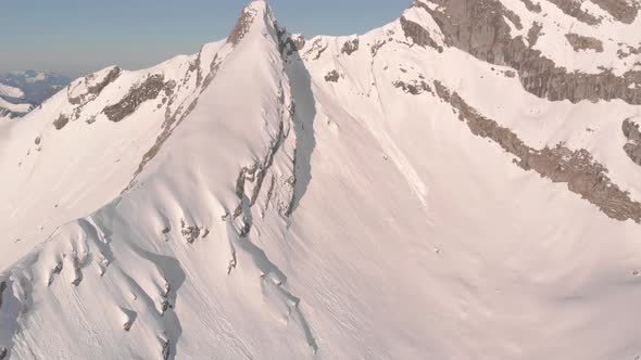 Flying over a large, snow covered mountain to look over a mountain range