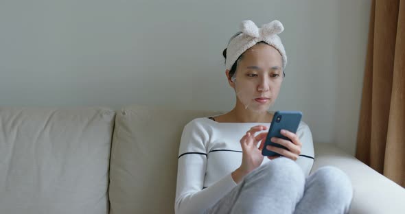 Woman Use of Mobile Phone with Paper Mask at Home