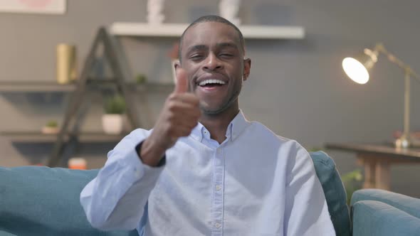 Portrait of African Man Showing Thumbs Up While Sitting on Sofa