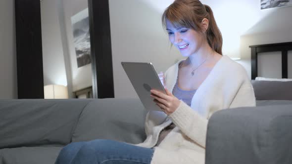 Reaction to Success by Woman Using Tablet in Bedroom