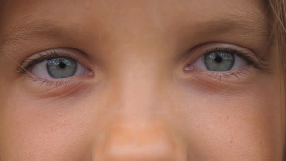 Blue Eyes of Beautiful Small Girl Blinking and Looking Into Camera with a Sad Sight. Portrait of