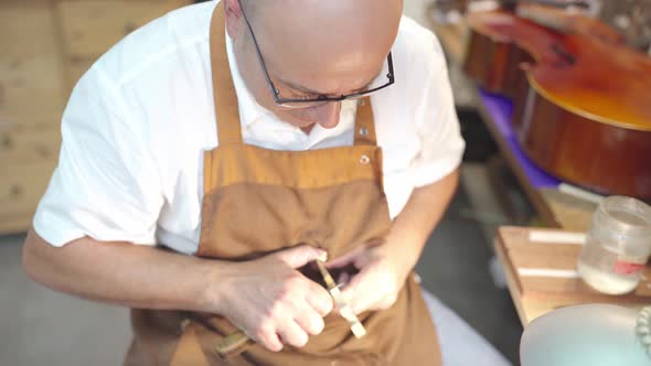 Luthier with violin bridge in workshop