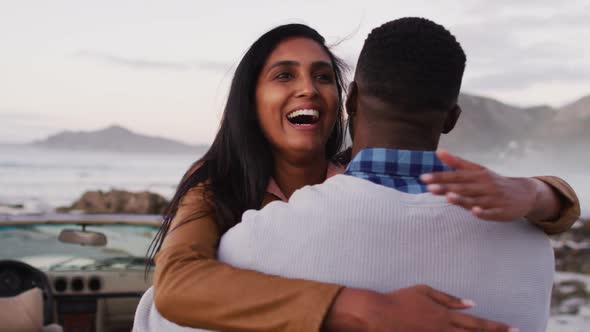 African american couple hugging each other near the convertible car on the road