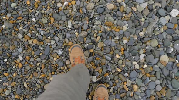 Man in Brown Sport Shoes Walks on Pebbles