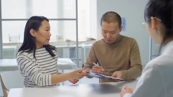 Asian Couple Signing Contract in Pregnancy Clinic