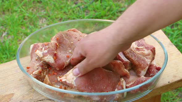 A Man's Hand Lays Out Fresh Meat in a Dish with Spices