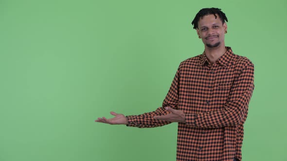 Happy Young Handsome African Man Showing Something and Giving Thumbs Up