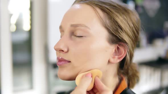 Side View of a Blonde Young Girl Getting a Make Up From Professional Make Up Artist