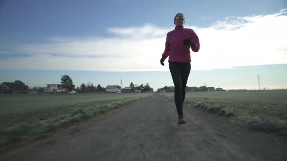 Woman Running on Dirt Track in Autumn Front View