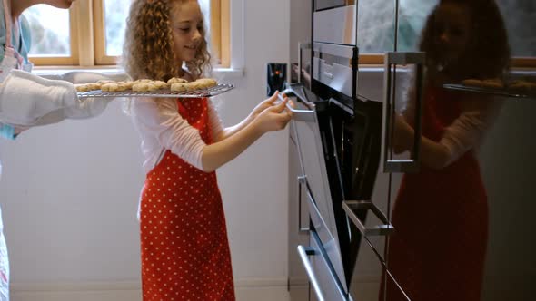 Mother and daughter are putting cakes in the oven