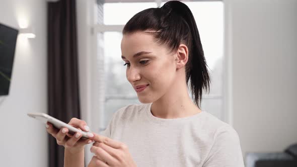 A smiling woman using her mobile while taking photo of salad