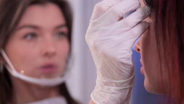 In the Beauty Studio the Beautician Aligns the Eyebrows to the Client Closeup