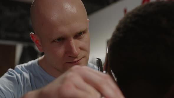 Closeup of Barber Cutting African American Guy's Haircut with Scissors in Barbershop