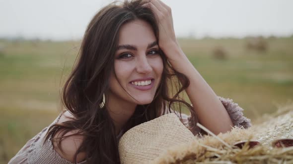 Girl in a Field Looking Around and Smiling at the Camera in Windy Weather