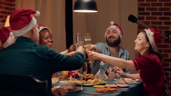 Festive Diverse People Wearing Traditional Hats While Clinking Champagne Glasses at Christmas Dinner