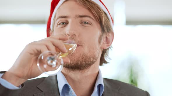 Handsome Young Blond Businessman Wearing Christmas Hat Drinking Champagne Smiling Winking Over