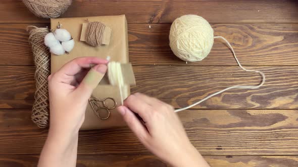 Girl's Hands Wind White Yarn on Piece of Cardboard