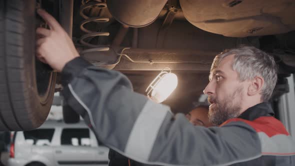 Auto Mechanics Checking Wheels of Car