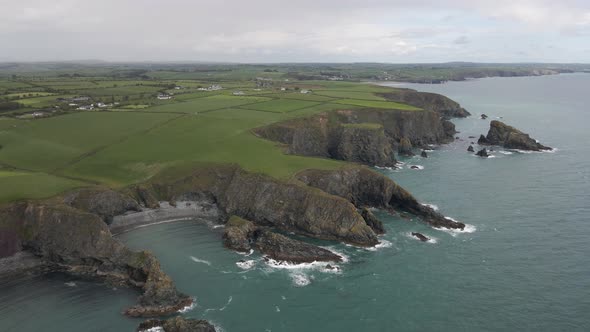 Drone shot of a coastline in rural Ireland with many sea cliffs, beaches and rock formations on a cl