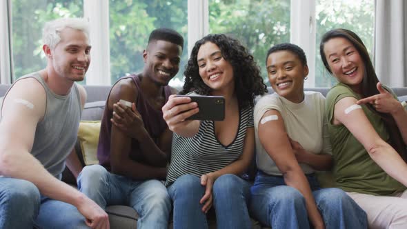 Group of diverse young people showing their vaccinated shoulders and taking a selfie at home