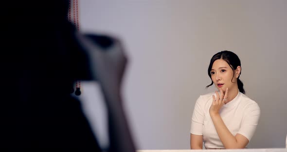 Beautiful Asian Female Model Posing For Commercial Product Shooting With Photographer At Studio.