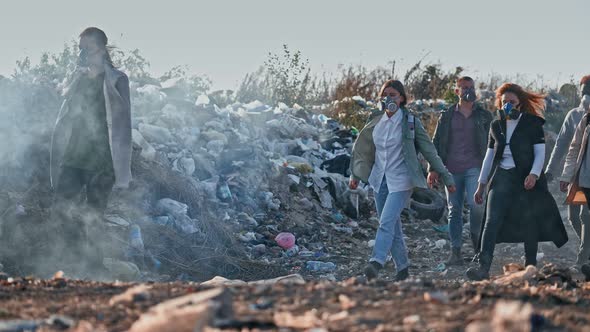 Group of Young People in Gas Masks Going Through the Toxic Smoke in a Garbage Dump