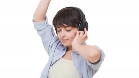 Young Smiling Caucasian Female with Short Hair Wearing Headphones Listening Music Dancing Having Fun