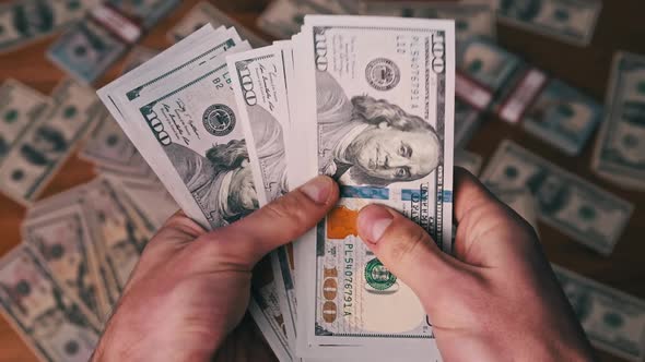 Dollars in Male Hands on Background of Table with Money Counting Banknotes