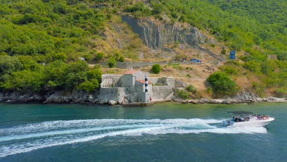 A Lighthouse with Black and White Stripes Against the Background of Mountain and Blue Sea with