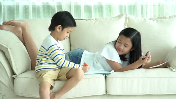 Asian Children Drawing Together In Living Room