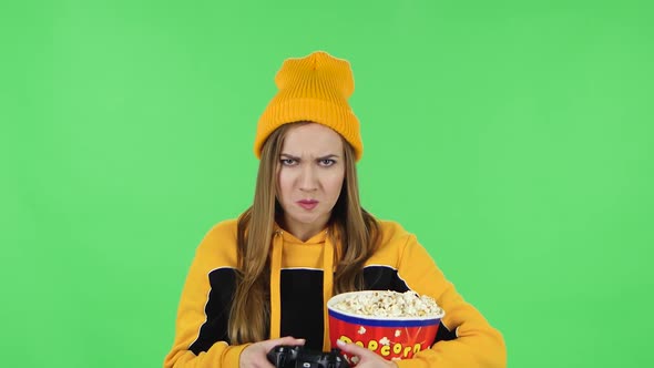 Portrait of Girl with Popcorn Is Playing a Video Game Using a Wireless Controller and Rejoicing in