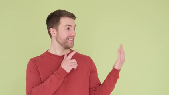 Cheerful American Guy Points His Finger at Empty Space for Copy Isolated Background in Studio