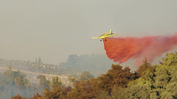 Fire fighter plane drops fire retardant on a forest fire in the hills