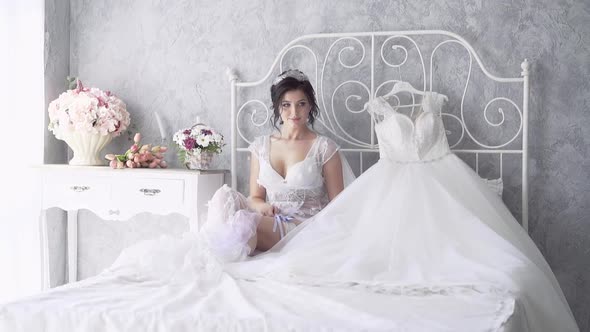 Slow Motion Bride in Lacy Dressing Sits Near Wedding Dress