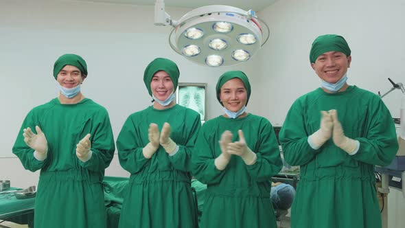 Group of Asian doctors remove mask, working in Hospital operating room with success and clap hands.