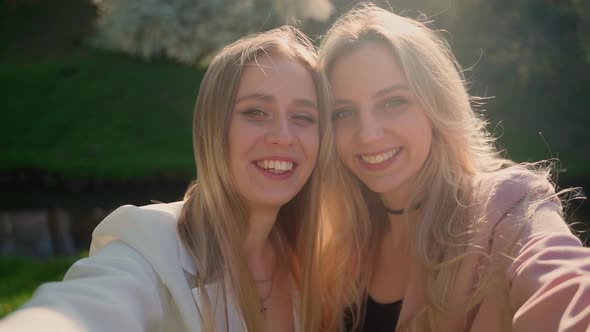 Two females making selfie on smartphone outdoors. POV shot of girlfriends looking at camera smile