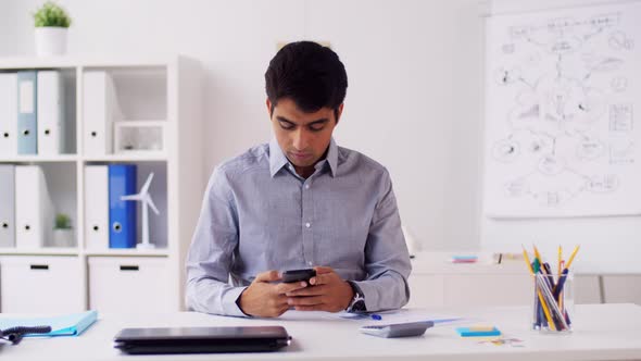 Businessman with Smartphone and Chart at Office 