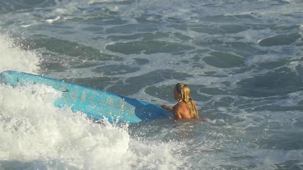 A young woman surfing in a bikini on a longboard surfboard.