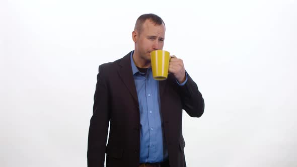 Man takes a sip of coffee and gets an upset stomach on white background.