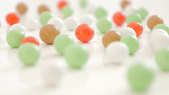Bonbons arranged on white reflective background 4K 2160p UltraHD footage - Shiny candies  on white s