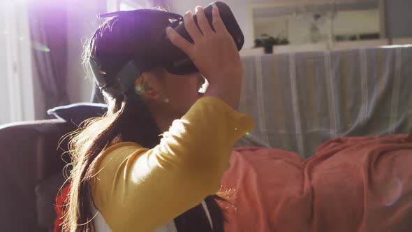 Happy asian girl at home, sitting on floor in living room using vr headset