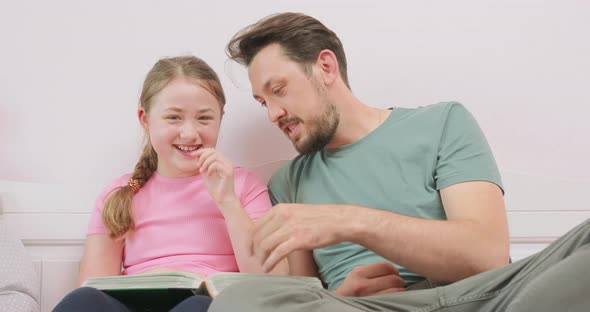 Close Up of Father and Laughing Teen Daughter Sitting on the Sofa and Looking at the Photo Album