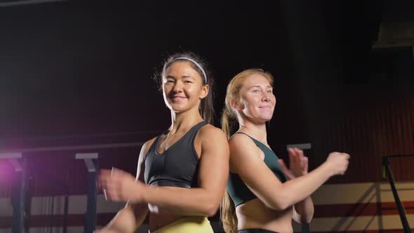 Two Strong Women in Sports Tops Put Their Hands on Their Belts Look at the Camera and Smile