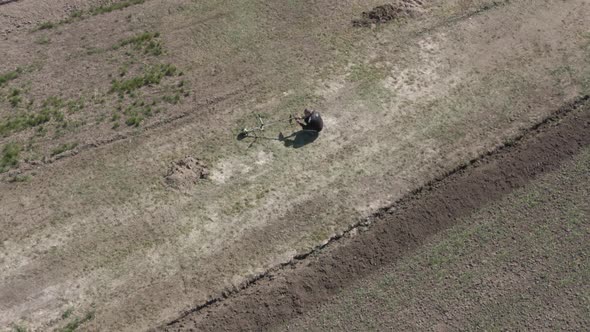 Drone View of Man Walking on Agricultural Field After Adjusting Lawn Mower