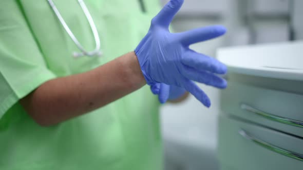 Hands of Unrecognizable Doctor Putting on Medical Gloves in Slow Motion Indoors