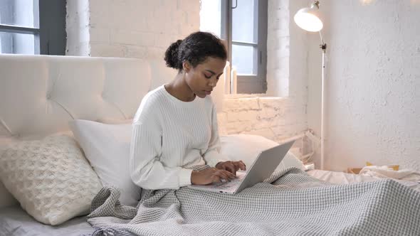 Young African Girl with Back Pain Working on Laptop in Bed